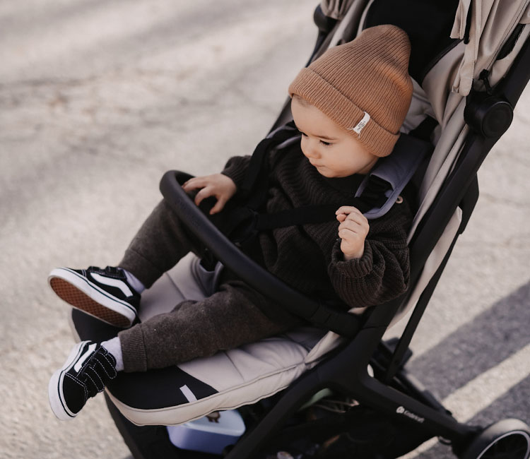 Chłopiec ubrany w czapkę i jesienne ubranko siedzący w wózku spacerowym NUBI 2