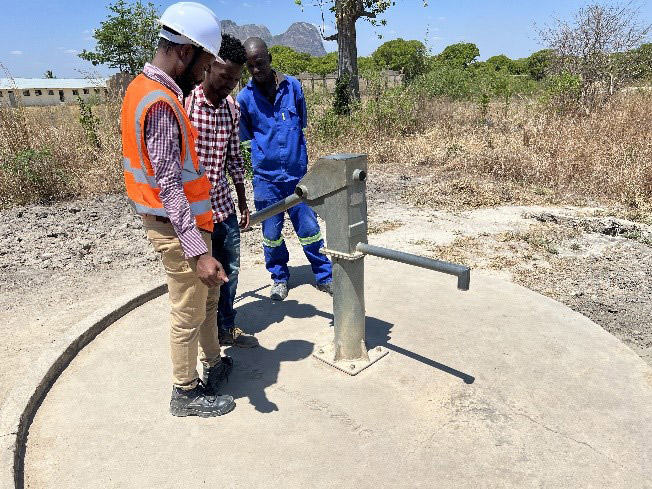 Robotnicy stojący nad nowowybudowaną pompą wodną w Mozambiku