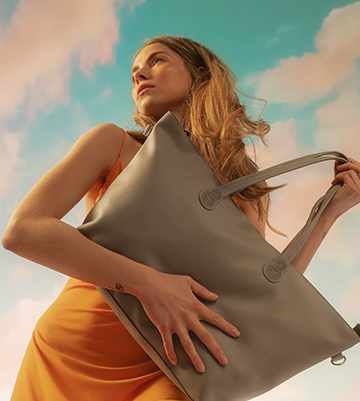 Mujer contra las nubes con un bolso de la exclusiva colección Nature Vibes