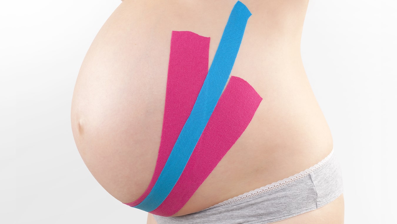Ciążowy brzuch oklejony profesjonalnymi taśmami tapeing żeby ulżyć w bólu pleców