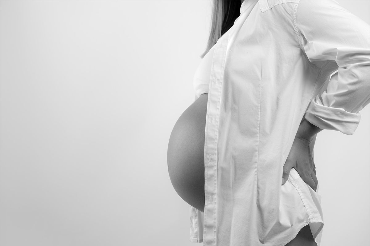 Kobieta w ciąży, zbliżenie na ciążowy brzuch, czarno-białe zdjęcie