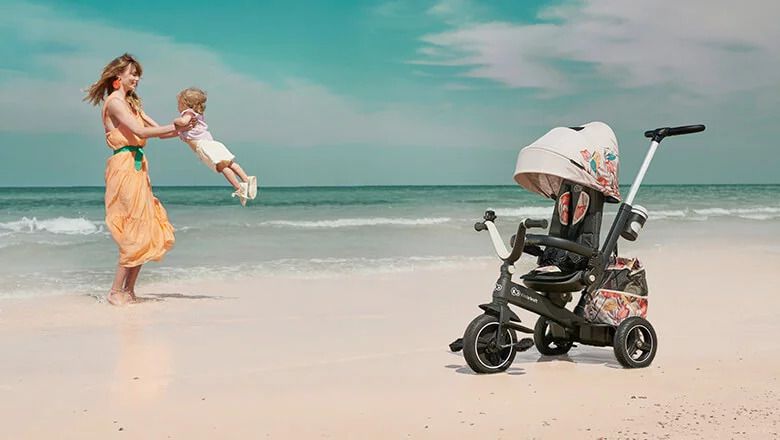 Kobieta z dzieckiem na plaży koło rowerka trójkołowego